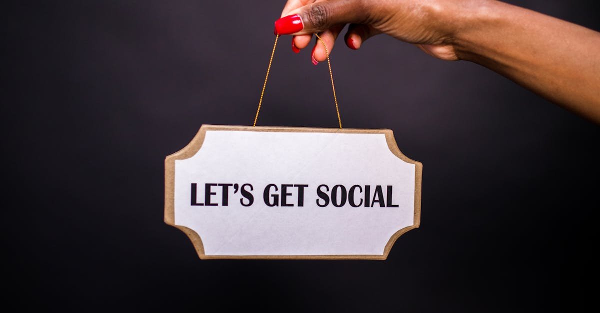 Close-up of a hand holding a sign with 'Let's Get Social' on a dark background.